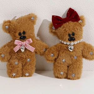 Close-up of brown plush bears with velvet bows, silver stars, and pearl heart necklace