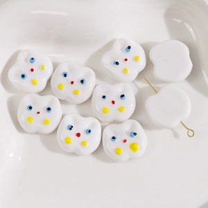 Close-up of hand-painted white acrylic cat beads for DIY earring and jewelry making