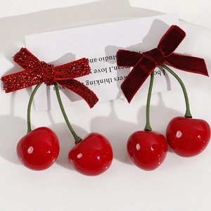Detail view of red velvet and glitter bow hair accessories with 3D cherry pendants