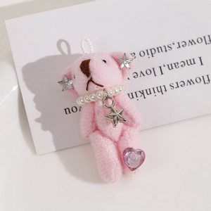 Detail of pink plush bear keychain with pearl necklace and silver star pendant