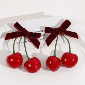 Sweet red velvet bow cherry earrings with glossy red fruit and green stems on tray