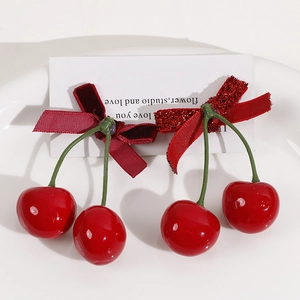 Detail of sweet cherry hair accessories with velvet bows and glossy red fruit charms