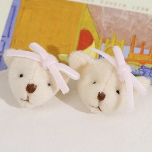 Detailed close-up of plush cream bear accessories with pink satin bows for DIY hair clips