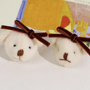 Macro shot of plush cream bear charms with velvet bows for DIY hair accessories