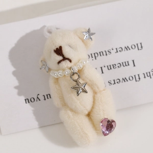Plush cream bear keychain with pearl necklace and star pendant in a cozy aesthetic setting