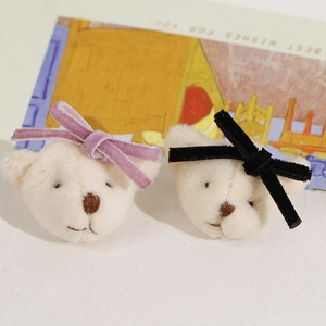 Detail view of plush cream bear charms with purple and black velvet bows for hair DIY
