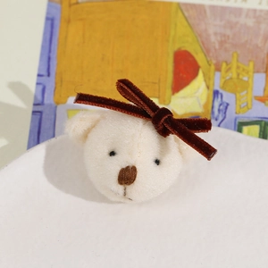 Close-up of cute plush cream bear with velvet bow and fine embroidered facial details