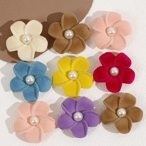 Flat lay of colorful velvet flower accessories with pearl centers for DIY jewelry making