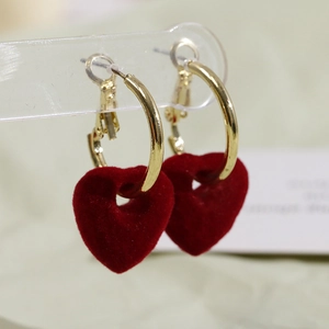 Detalle macro de colgantes de corazón flocados rojos en aros dorados redondos