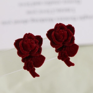 Elegant flocked burgundy rose earrings with detailed petals on an acrylic display
