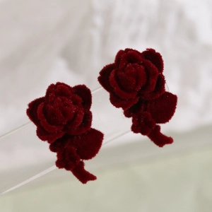 Macro shot of deep red flocked velvet rose earrings with layered petals and soft texture