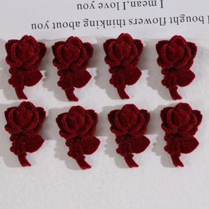 Close-up of eight pieces of dark red flocked acrylic rose charms for DIY jewelry