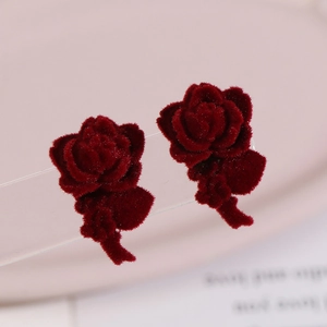 Macro detail of wine red velvet rose earrings with layered petals and soft flocking texture