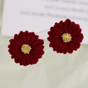 Macro detail of dark red velvet daisy earring with a matte golden floral center