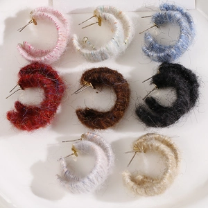 Detail of colorful plush yarn-wrapped C-shape stud earrings in eight various seasonal tones