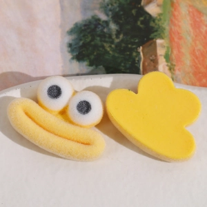 Gros plan de charms en peluche jaune avec de grands yeux et accessoires en résine