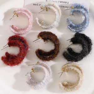 Detail view of plush yarn-wrapped C-shaped earrings in assorted warm autumn colors
