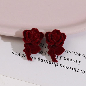 Macro shot of flocked burgundy rose earrings with textured petals and velvet finish