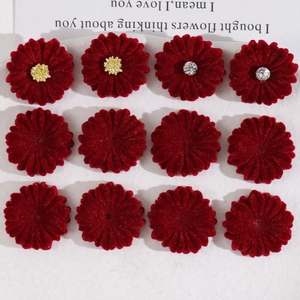 Close-up of 12 red velvet daisy flower charms with crystal and yellow stamen accents