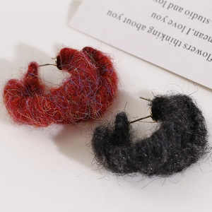 Macro shot of fluffy yarn-wrapped semi-circle stud earrings in red and black colors