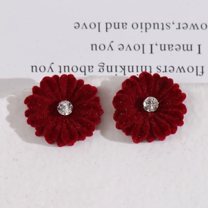 Detailed view of red velvet daisy stud earrings with central crystal on white background