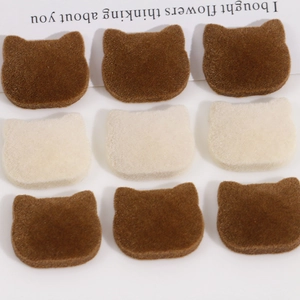 Close-up of brown and beige flocked cat head resin patches for DIY hair accessories