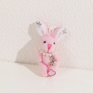 Vue détaillée d'un lapin en peluche rose avec collier de perles et rivets étoiles