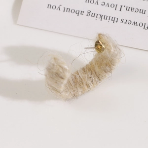 Macro shot of cream plush yarn-wrapped C-shaped hoop earring with gold metal posts