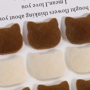 Macro detail of flocked cat-shaped DIY accessories in brown and cream white colors