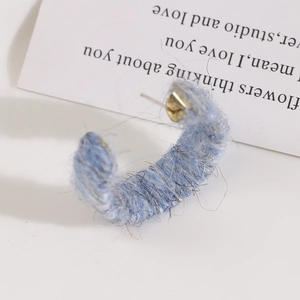 Detailed view of blue plush yarn wrapped C-shaped earring with golden metal post