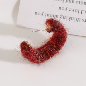 Detail showing red plush yarn-wrapped C-shaped earring with colorful metallic fibers
