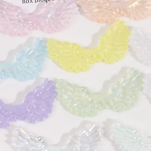 Macro shot of glittery resin angel wings DIY charms in pastel gradient starry colors