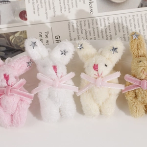 Détail de quatre breloques lapins en peluche colorées avec nœuds en satin et étoiles