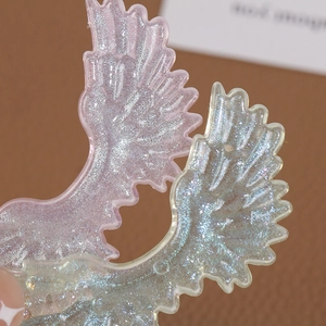 Macro shot of glittery acrylic angel wings with gradient purple and teal shimmer texture