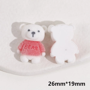 Macro detail of white flocked bear DIY charm with red sweater and BEAR text engraving