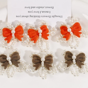 Macro shot of handmade pearl flower hair bows with orange and brown flocking detail