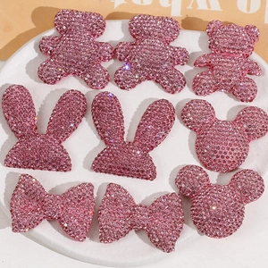 Close-up of pink rhinestone resin bear and bow patches for DIY accessory making