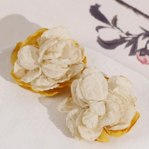 Detailed macro view of handmade cream and yellow fabric camellia flower accessories