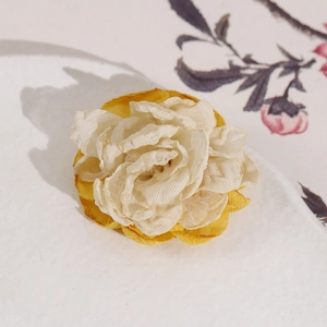 Detailed macro view of handmade cream lace and yellow fabric rose floral accessory