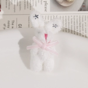 Gros plan d'un pendentif lapin en peluche blanc avec nœud rose et détails étoilés