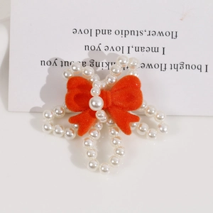 Close-up of handmade white pearl petals with a vibrant orange velvet bow accessory