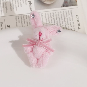 Vue détaillée d'un lapin en peluche rose avec nœud en velours et étoiles argentées