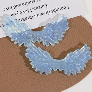 Macro shot of glittery blue resin angel wing charms with layered feather texture
