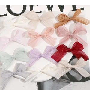 Detail of 12 glitter organza bow clips in multiple colors like ivory and champagne