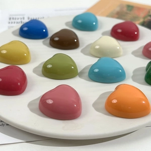 Close-up of colorful heart-shaped resin charms in a white tray for DIY crafts