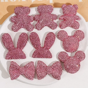 Pink glitter resin DIY accessories with teddy bear, bunny, and bow shapes in a white tray