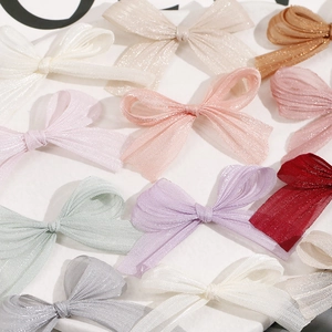 Close-up of assorted multi-color shimmering mesh bow hair clips on a white tray