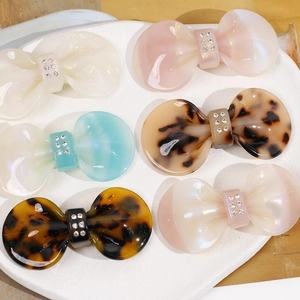 Close-up of assorted acetate bow clips with sparkling rhinestones in a ceramic dish