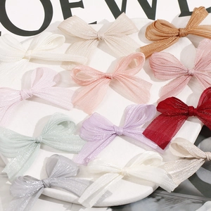 Detail of colorful shimmering mesh bow hair clips neatly arranged on a marble tray