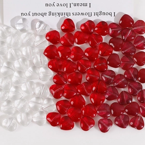Dettaglio macro di perline di vetro a forma di cuore rosse e trasparenti per gioielli